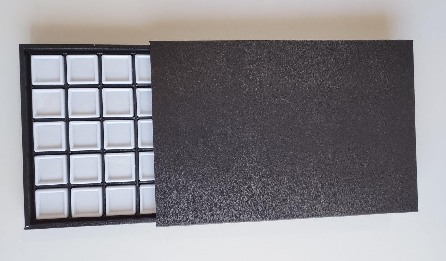 Black leather-style box with magnetic closure and sectioned interior. (28,5 * 19 * 3 cm)
